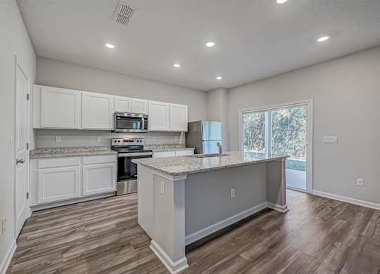 Modern kitchen with white cabinets, granite countertops, stainless steel appliances, and a central island.