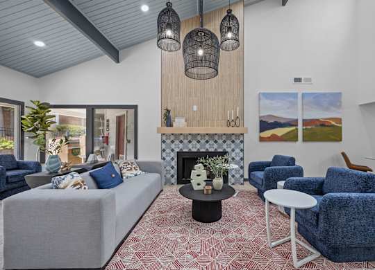A living room with a grey couch, blue chairs, and a fireplace.