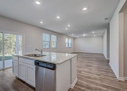 Open concept kitchen and living area with wood-look flooring, granite countertops, and stainless steel appliances.
