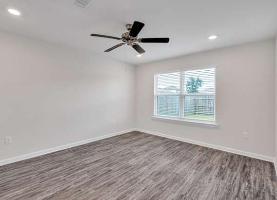 A room with a ceiling fan and a window with blinds.