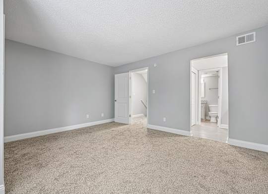 A room with a carpeted floor and a doorway leading to another room.