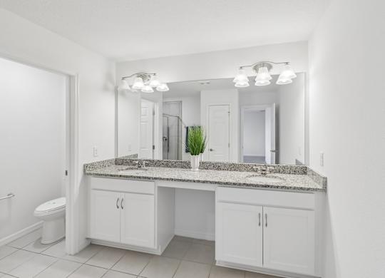A bathroom with a granite countertop and white cabinets.