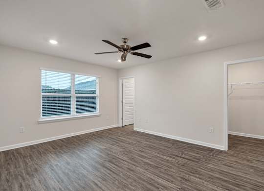 A room with a ceiling fan and a window with blinds.