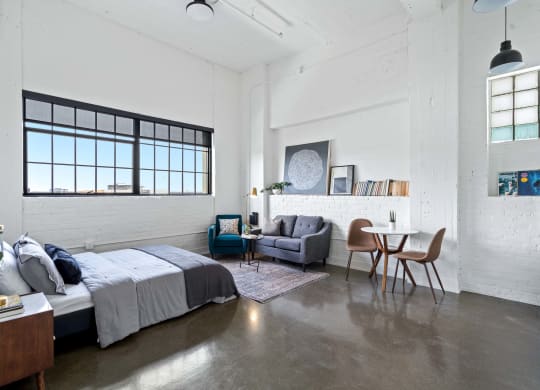 a bedroom with a bed and a living room with a table and chairs