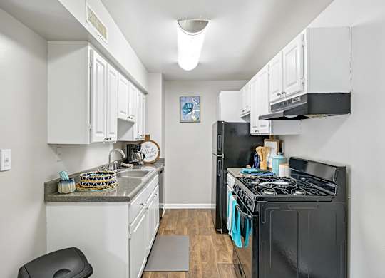 A kitchen with black appliances and white cabinets.