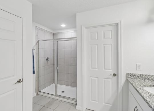 A white bathroom with a walk-in shower and a sink.