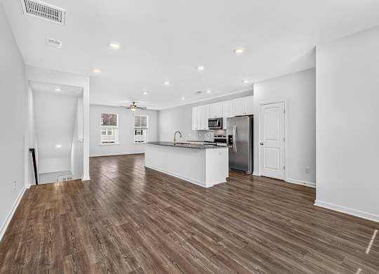 A spacious kitchen and living room with wood flooring.