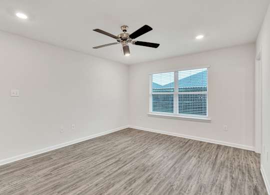 A room with a ceiling fan and a window with blinds.
