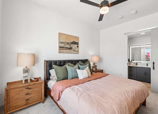 A bedroom with a bed, nightstand, and a ceiling fan.