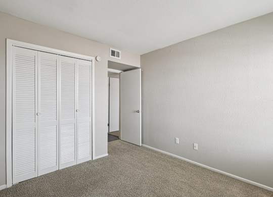 A room with a white door and a carpeted floor.