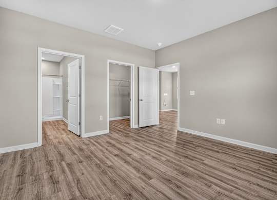 A room with three open doors and wood flooring.