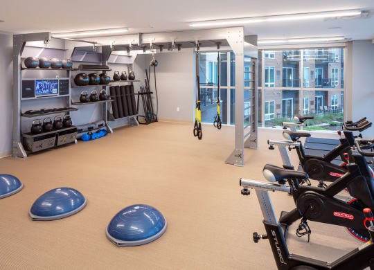 a large fitness room with cardio equipment and a large window