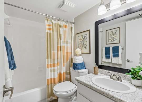 A bathroom with a toilet, sink, and shower curtain.
