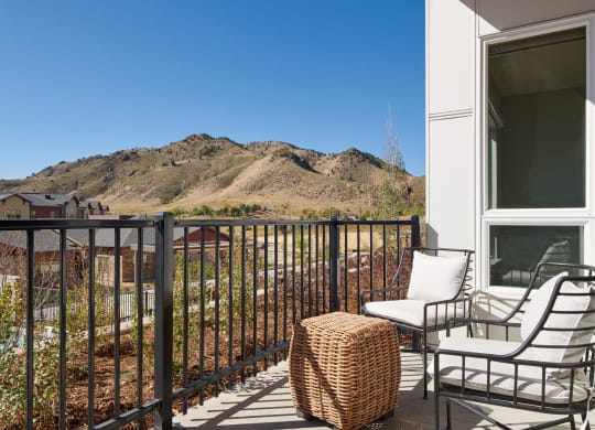 a balcony with two chairs and a table and a mountain in the background
