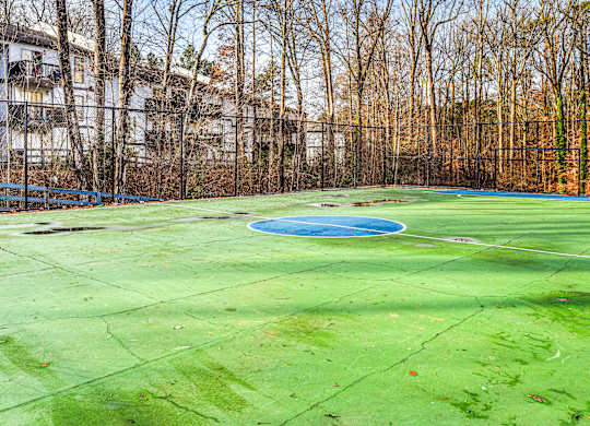 A green tennis court with a blue pool in the middle.