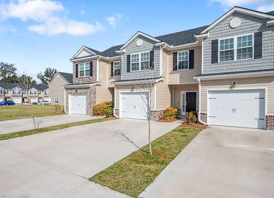 Omnia at Richmond Hill Townhomes in Georgia photo of exterior homes with white doors on a lengthy driveway