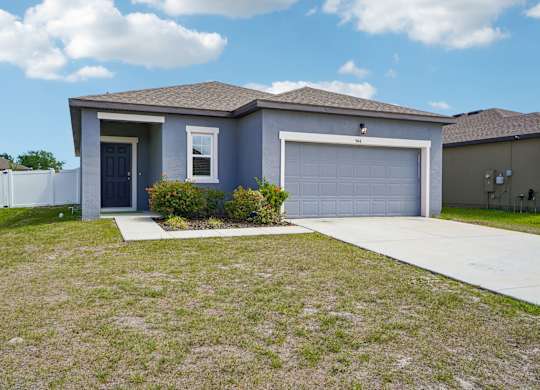 A house with a blue garage door and a white fence.