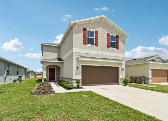 A house with a brown garage door and red shutters.