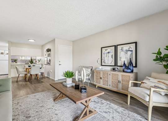 A living room with a white couch, a wooden coffee table, and a dining table with chairs.