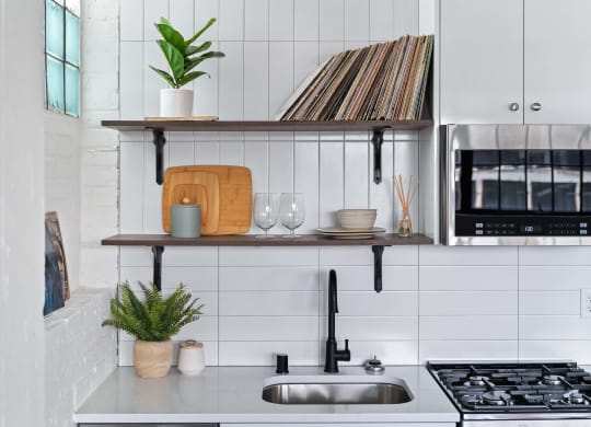 a kitchen with white tiles and a sink and a shelf