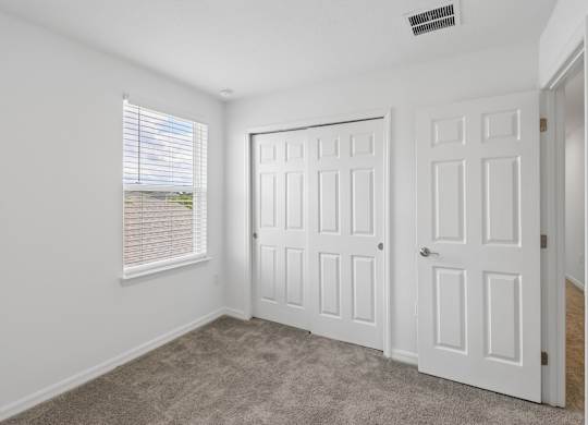 A room with two doors and a window with blinds.