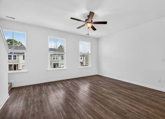 A room with a ceiling fan and wooden flooring.
