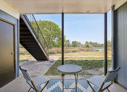 A patio with a table and chairs overlooking a river.