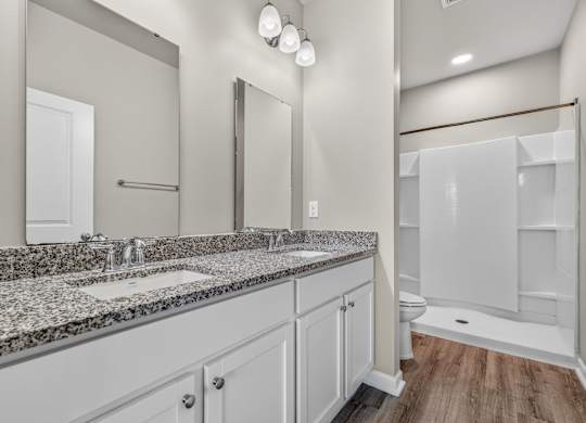 A bathroom with a granite countertop and white cabinets.