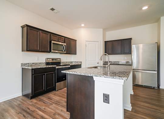 A kitchen with a granite countertop and stainless steel appliances.