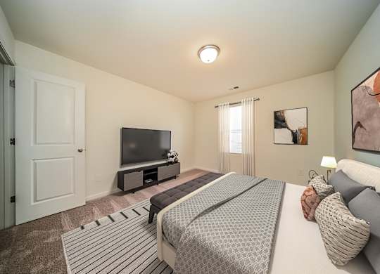 A bedroom with a bed, a television, and a painting on the wall.