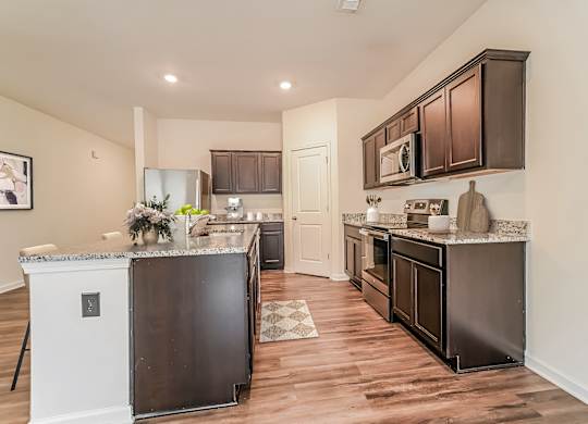 A kitchen with dark brown cabinets and a black refrigerator.