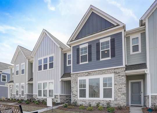 a row of townhomes with gray siding and a gray door