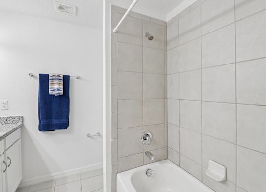 A white bathroom with a blue towel hanging on the wall.