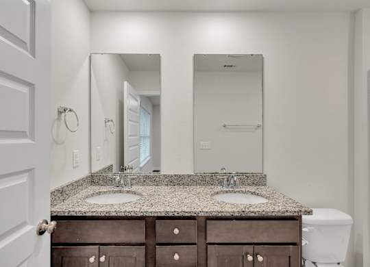 A bathroom with a granite countertop and a white toilet.