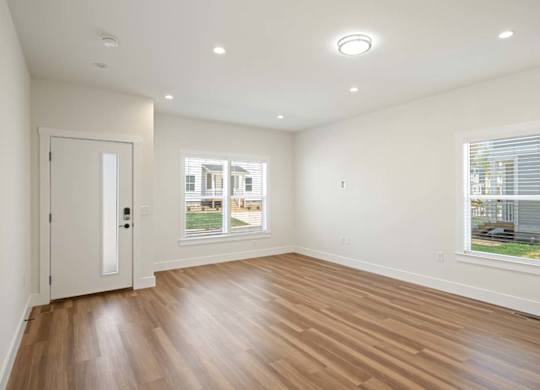 Spacious and bright living area with wood flooring and large windows in an Asheville home.