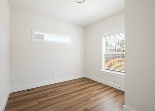 A room with wooden floors and a window with blinds.