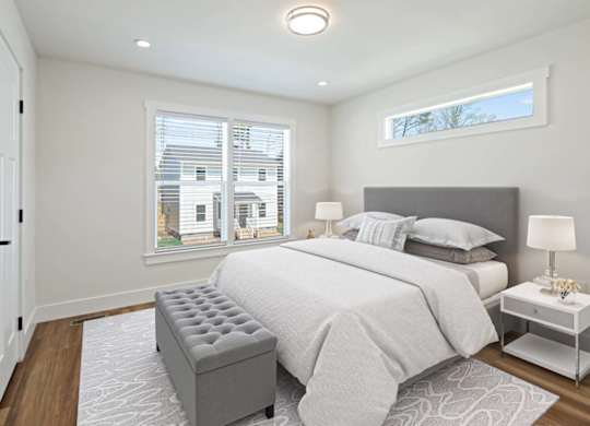 Bright bedroom at Belle Meadow with large windows, modern decor, and neutral tones.