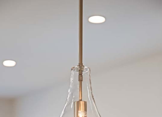 A clear glass pendant light with a single bulb hanging from a ceiling.