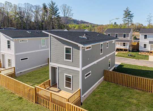 Aerial view of a fenced two-story home in Asheville with private yard and modern gray siding.