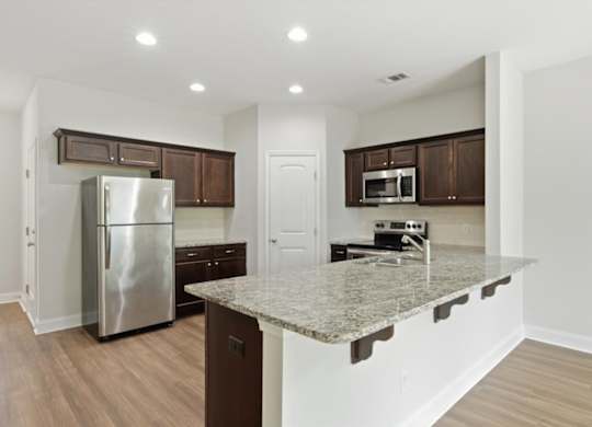 A kitchen with a granite counter top and stainless steel appliances.