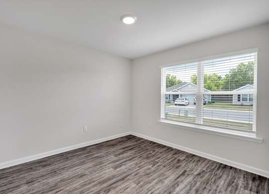 A room with a window and a view of a house and a car outside.