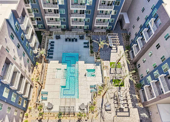 A swimming pool surrounded by buildings and palm trees.