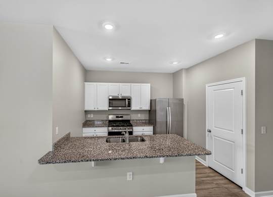 A kitchen with granite countertops and white cabinets.