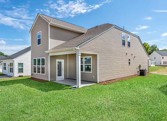 the back of a house with a lawn and a yard next to it