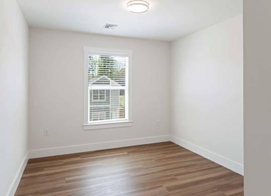 A room with a window and wooden flooring.