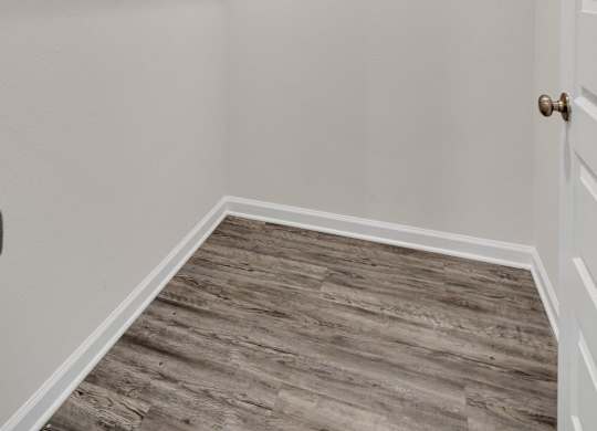 A walk-in closet with a wooden floor and white walls.