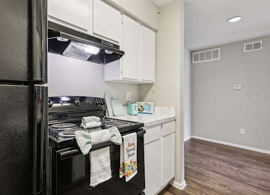 A kitchen with a black refrigerator and white cabinets.