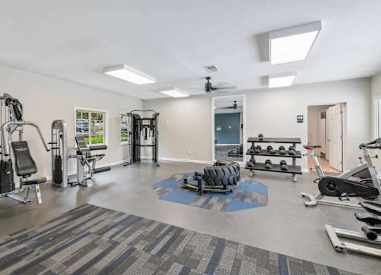 A gym with a variety of equipment including weights and cardio machines.