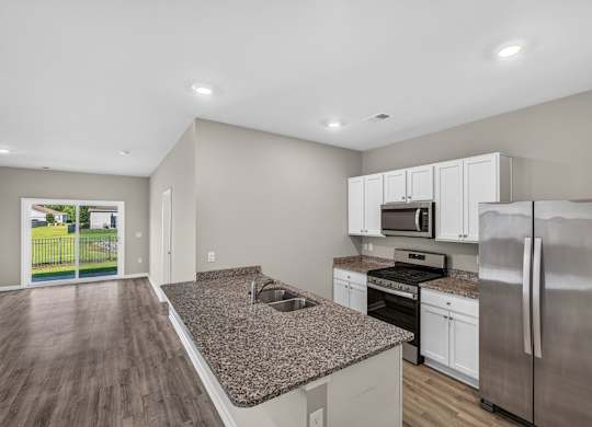 A kitchen with a granite countertop and stainless steel appliances.
