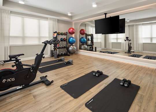 A home gym with a stationary bike, dumbbells, and a television.